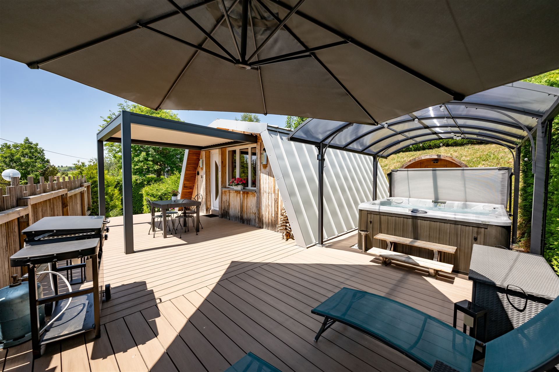 Terrasse en bois du chalet Au Doux Altic à Métabief avec jacuzzi couvert et espace détente