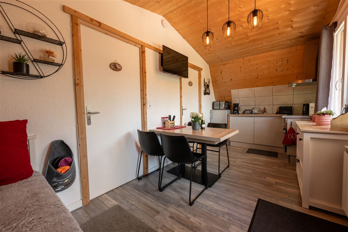 Pièce à vivre en bois avec kitchenette et table du chalet romantique Au Doux Altic
