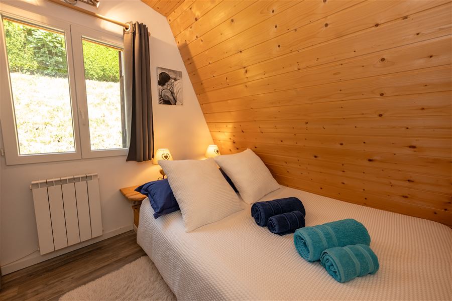 Chambre double avec mur en bois et linge blanc au chalet Au Doux Altic à Métabief