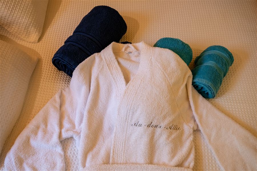 Peignoir blanc et serviettes préparées pour un accueil spa au chalet Au Doux Altic